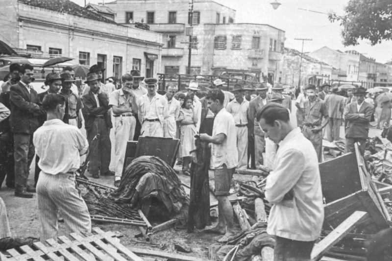 Na avenida Dr. Antônio Lobo, no meios de escombros, cidadãos observam tabuleta que trazia, provavelmente, informações sobre vítimas.