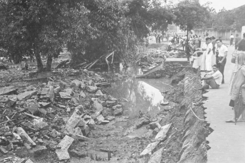 A foto mostra o local exato da morte de Domingos de Jesus e os destroços do muro que o atingiu; mais à frente pode ser visto o canal por onde as águas do Córrego do Parque entravam no terreno.